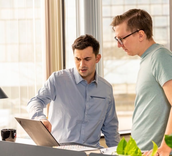 Two men looking at a laptop screen in an office.