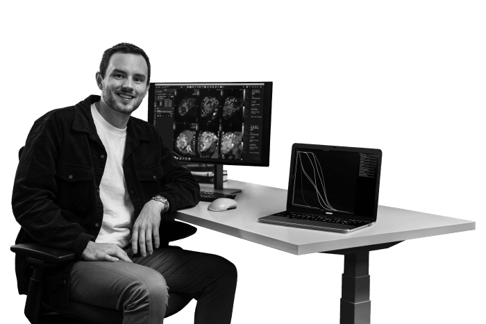 Man sitting at desk with a computer monitor showing medical scans. 